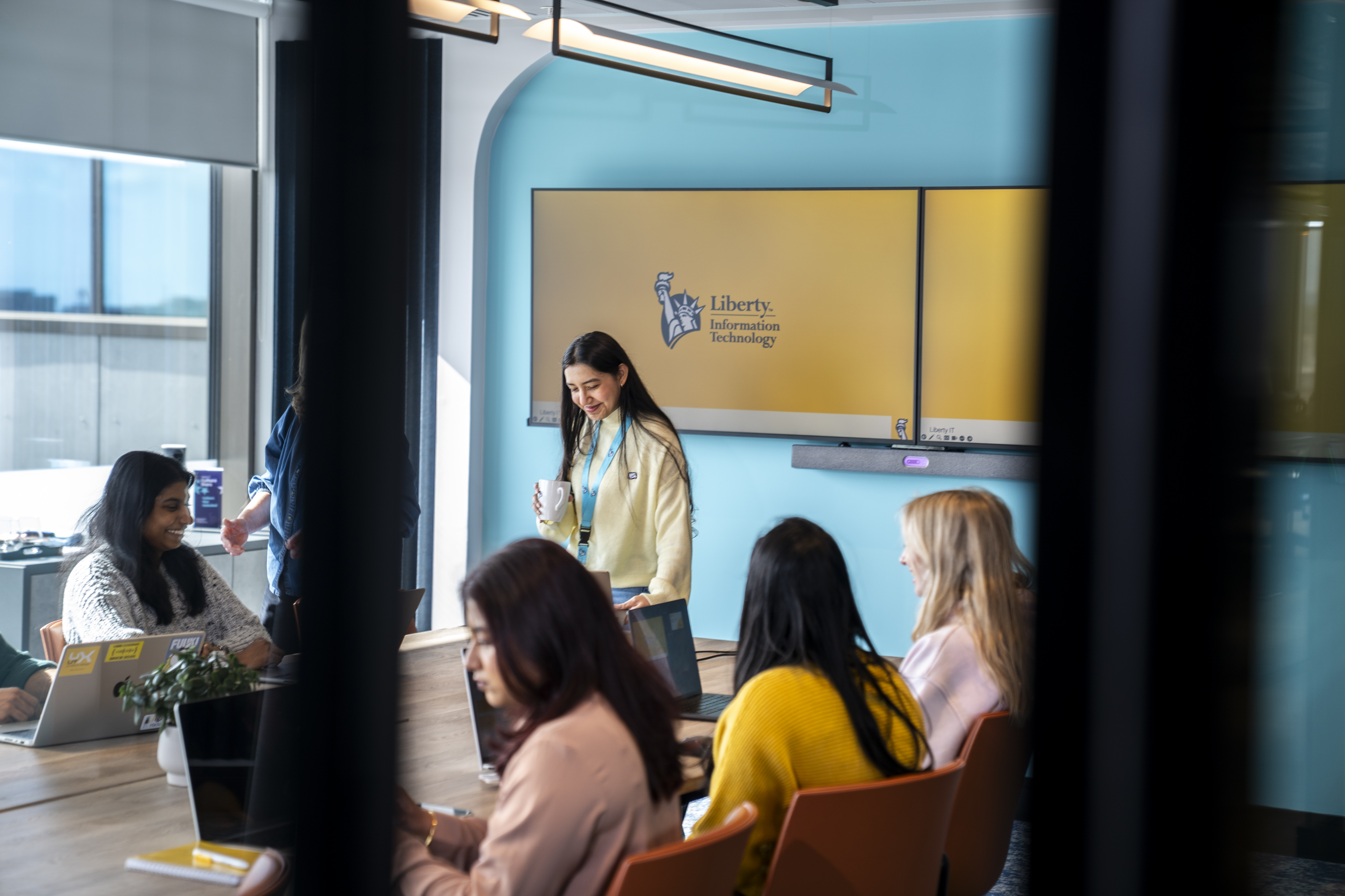 Employees meeting in a Liberty IT conference room with branded screens in the background.
