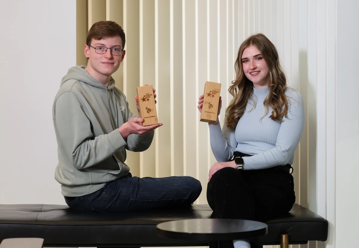 Shannon and Andrew in an office location holding up Culture Stars awards