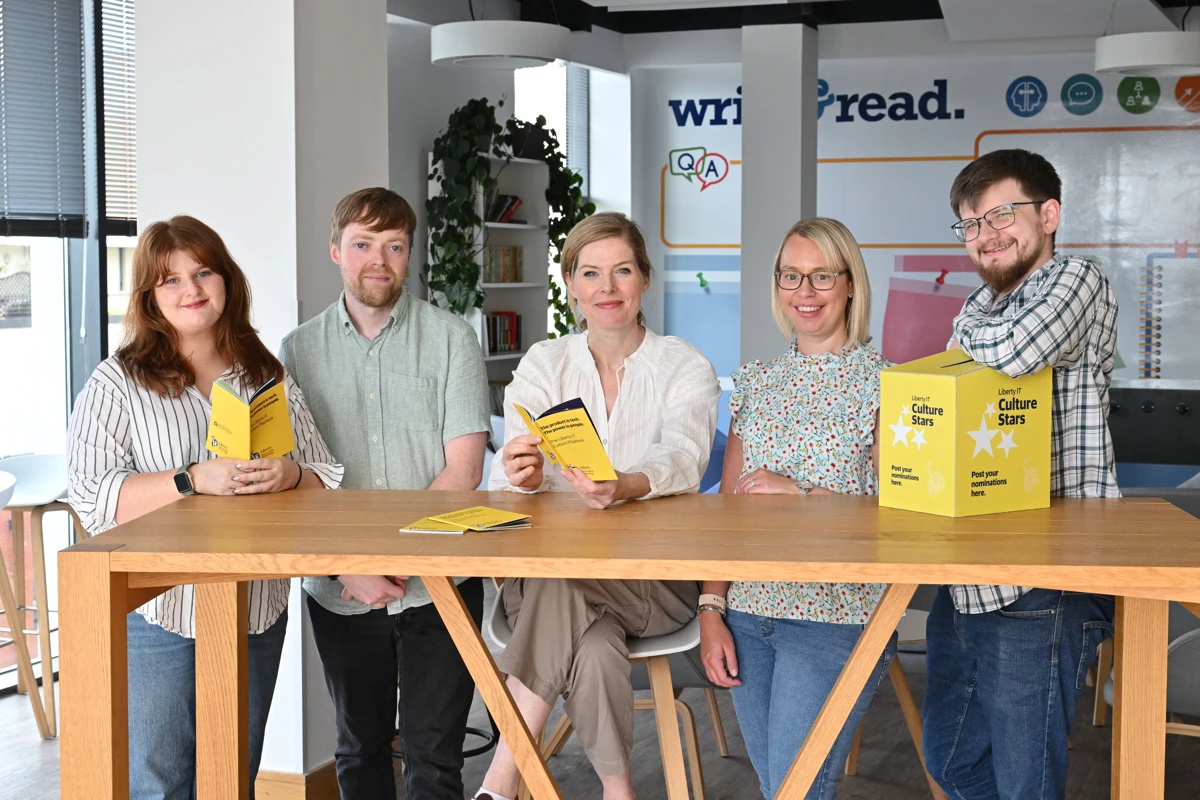 Five Liberty IT employees pictured in office setting with Culture Star books