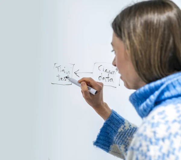 Employee in blue jumper writing on a whiteboard