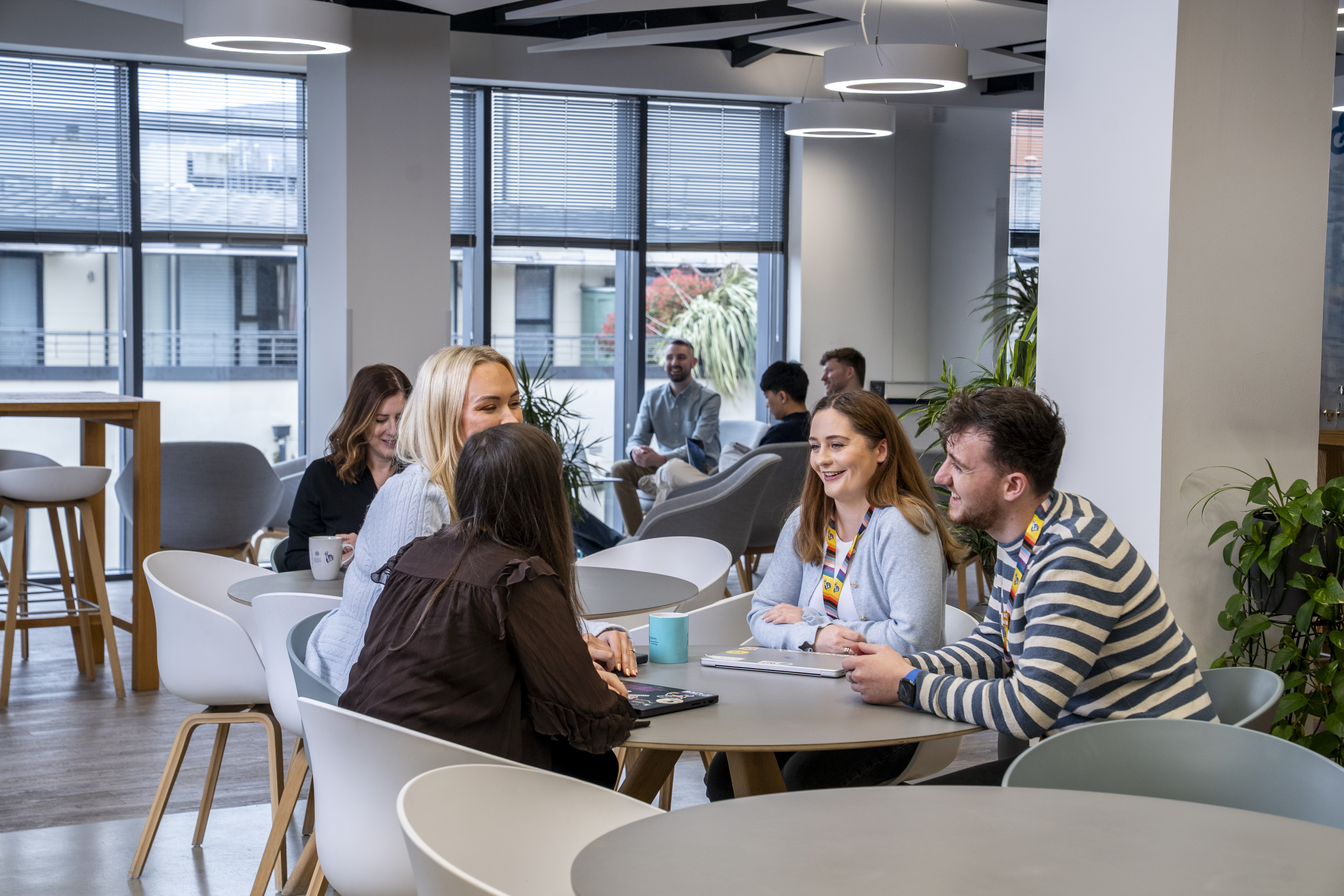 Employees socialising and collaborating in a shared workspace in the Liberty IT Belfast office.