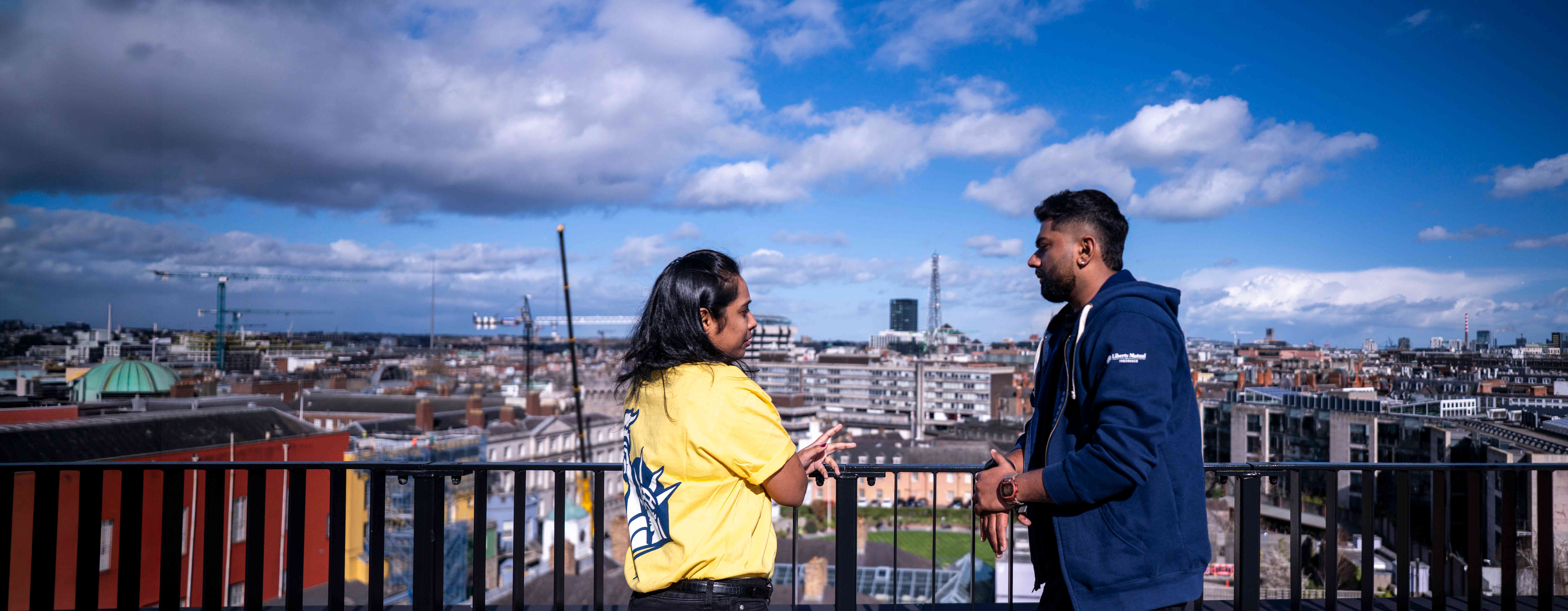 Employees talking on a rooftop terrace overlooking the Dublin skyline.