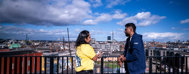 Employees talking on a rooftop terrace overlooking the Dublin skyline.