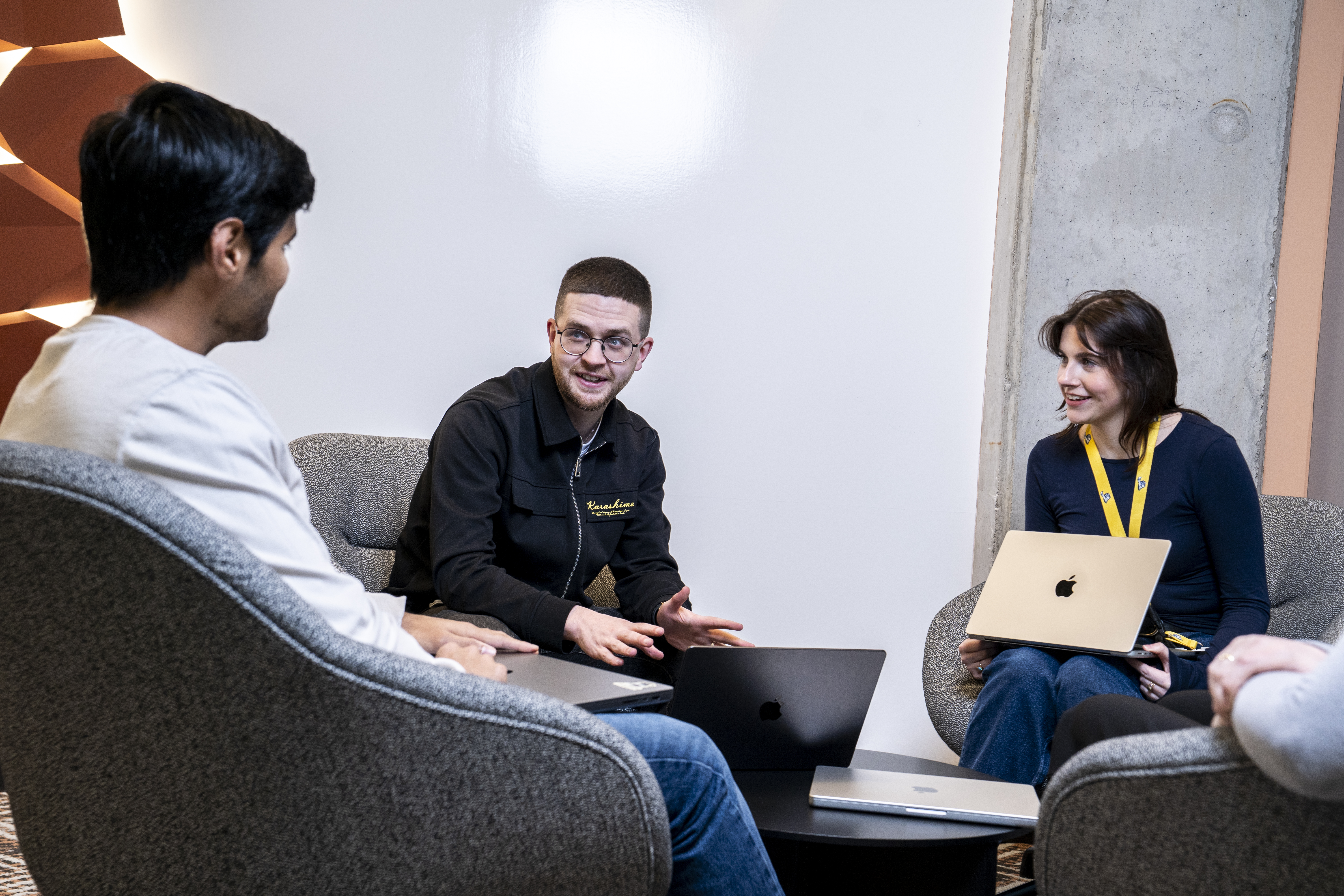 Three employees talking at a collaboration space in an office