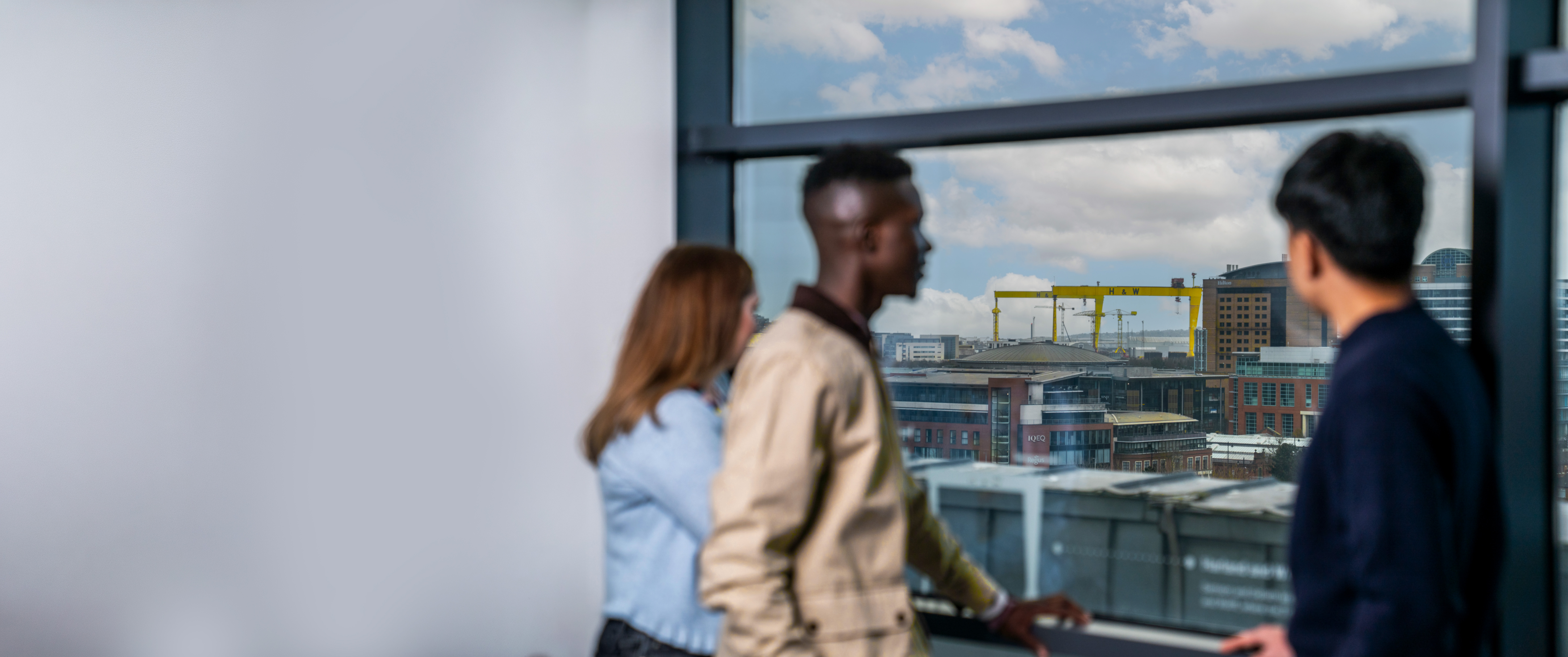 Employees looking out over the Belfast skyline from a Liberty IT office.