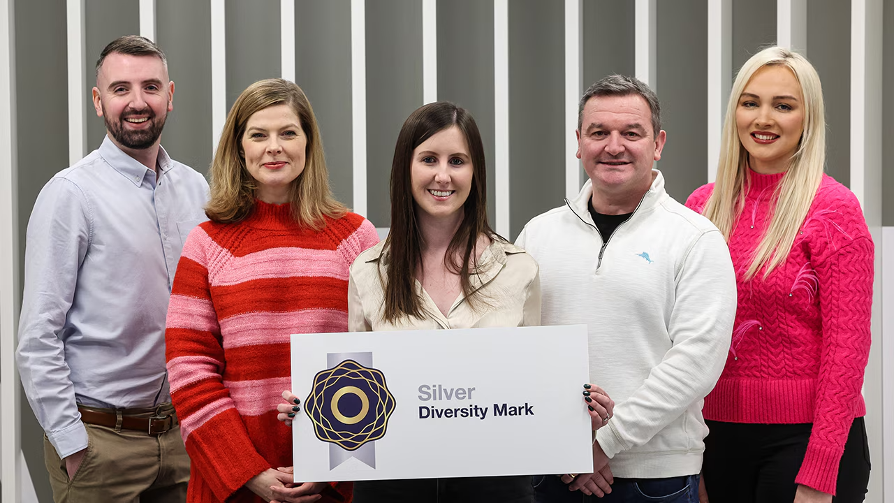 Five Liberty IT employees smiling with Silver Diversity Mark sign