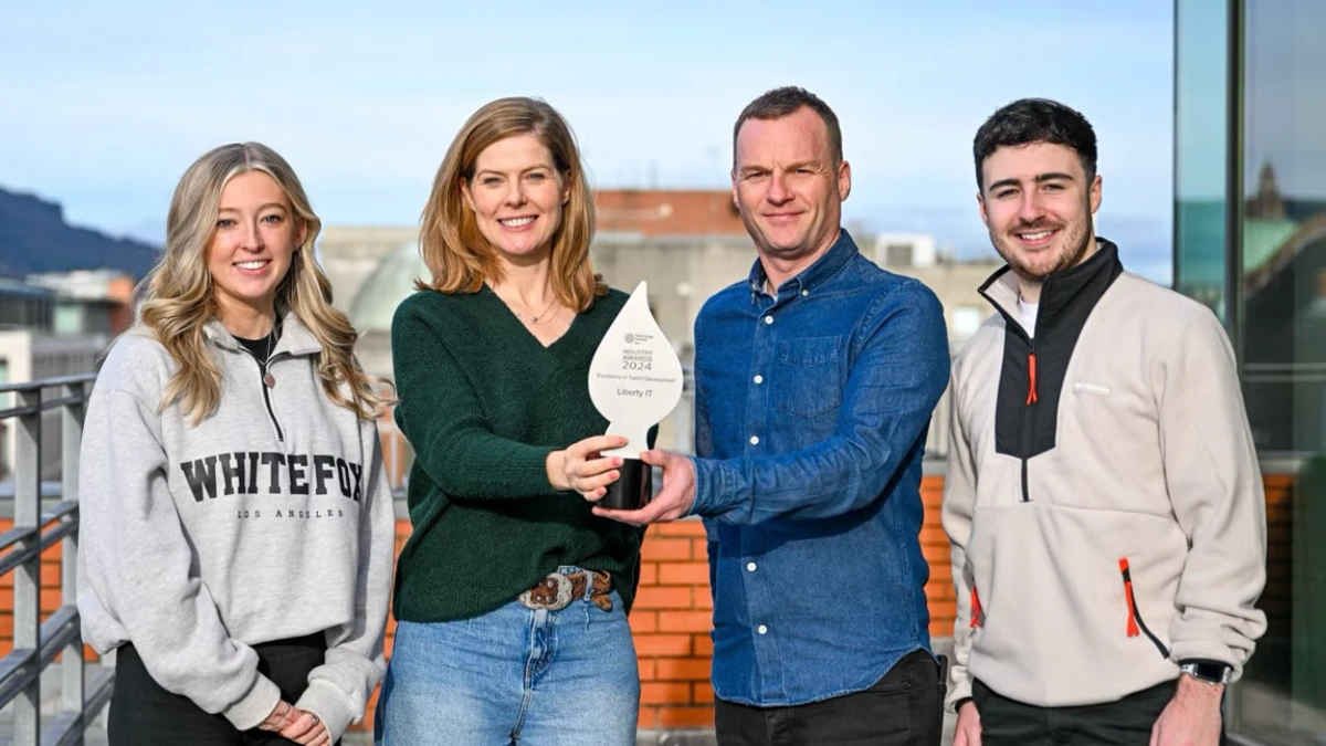 Four employees smiling on balcony with award
