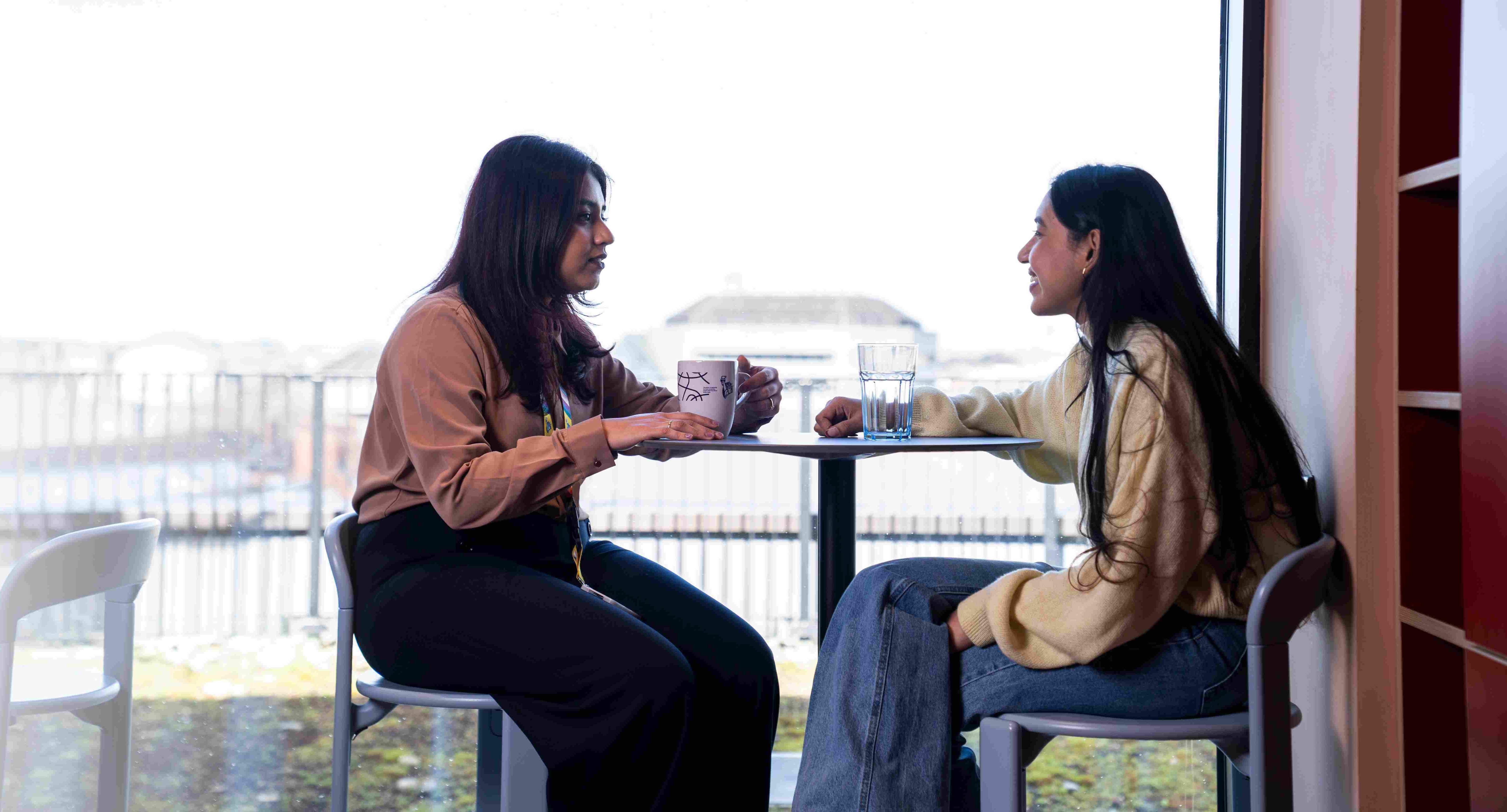 Two women having coffee in office