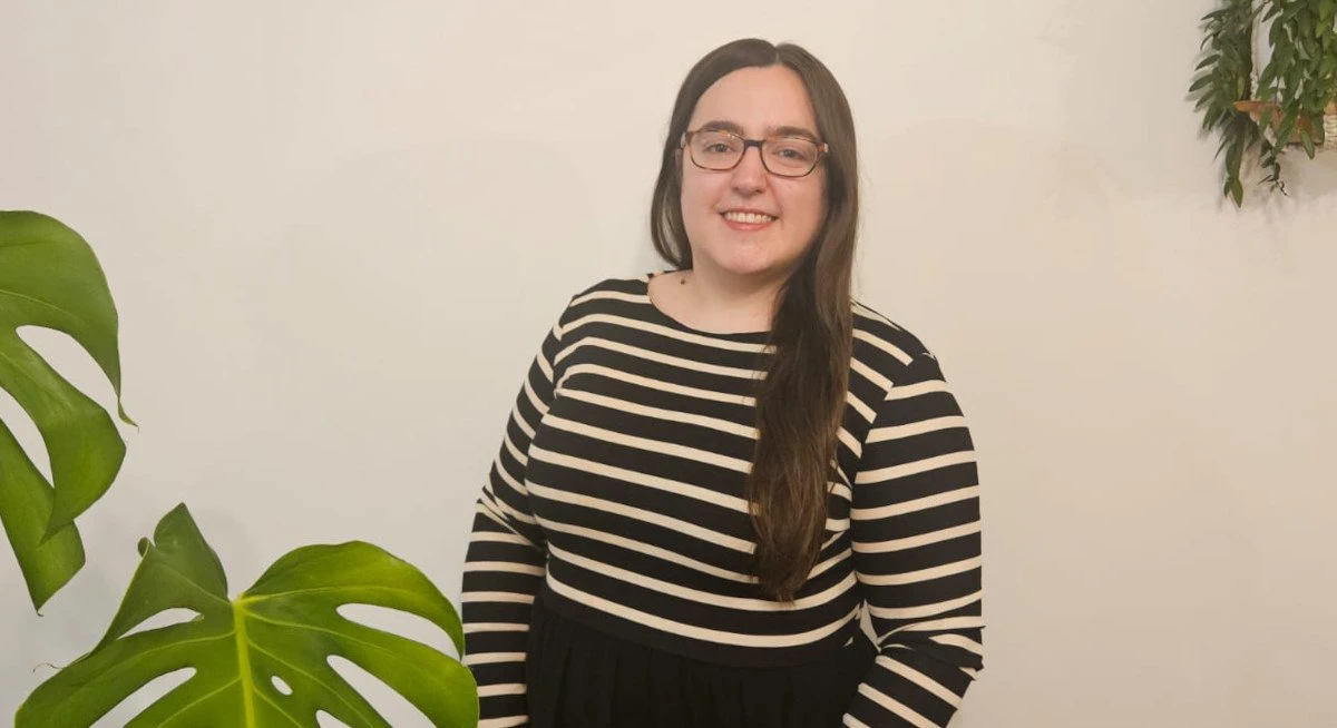 Sarah, Software Engineer smiling next to greenery
