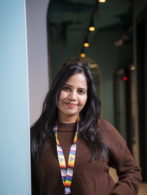 Gouri, a Liberty IT employee, smiling while wearing a Pride lanyard.

