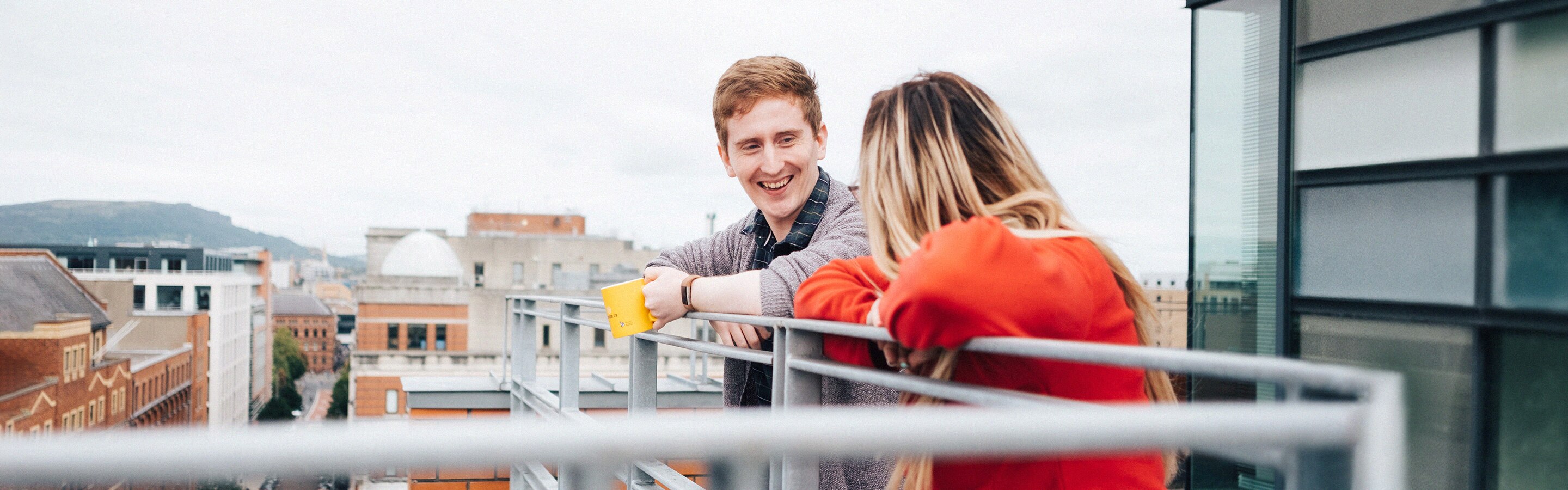 Photo of man and woman talking on office balcony