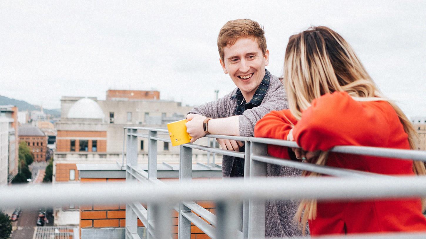 Photo of a man and woman talking on an office balcony