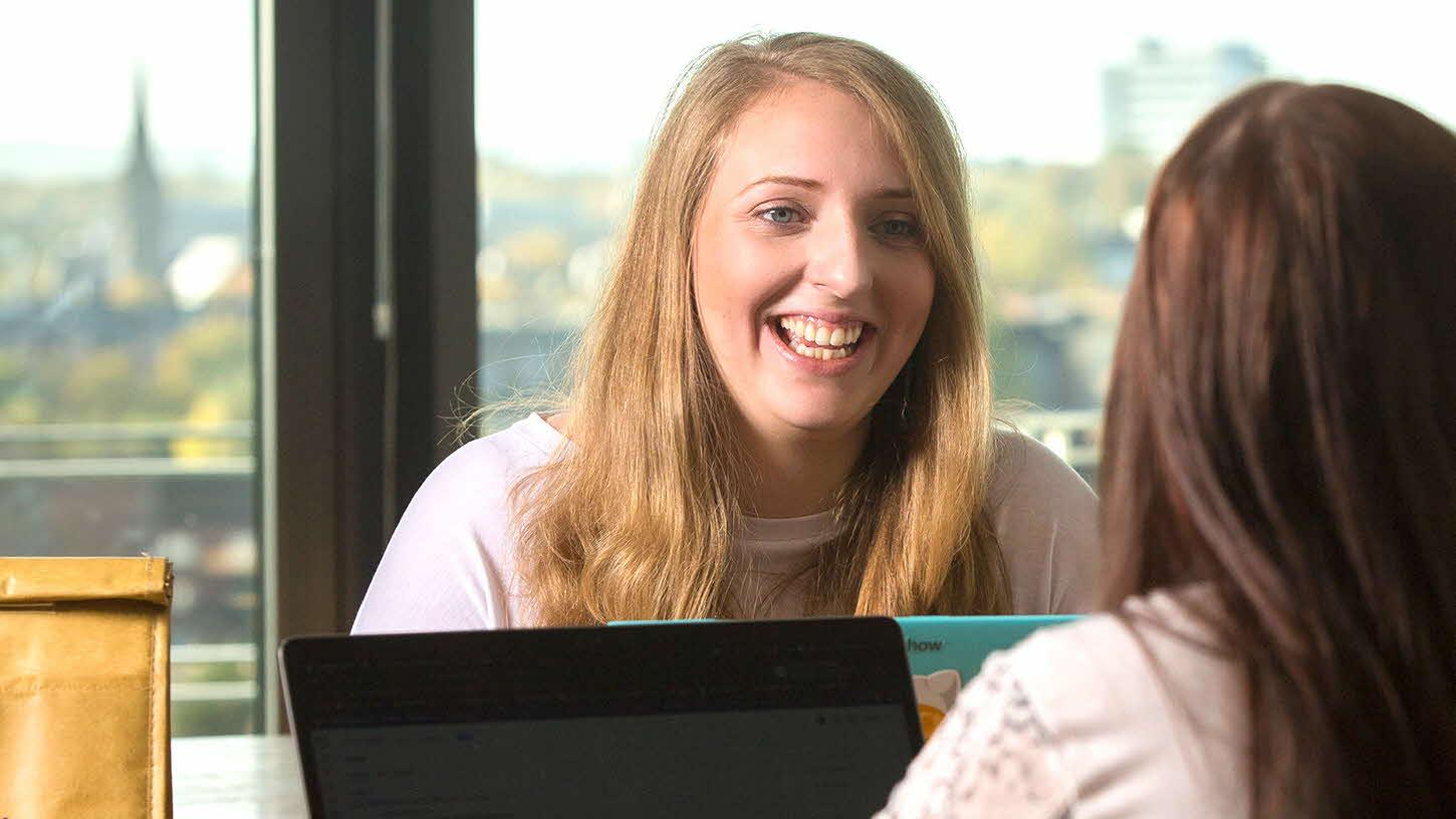 Two women talking over a laptop screen