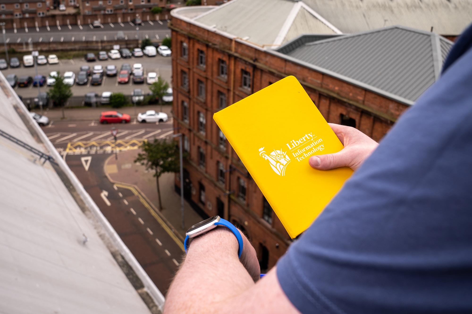 Photo of hand holding notebook, looking over street from high up 