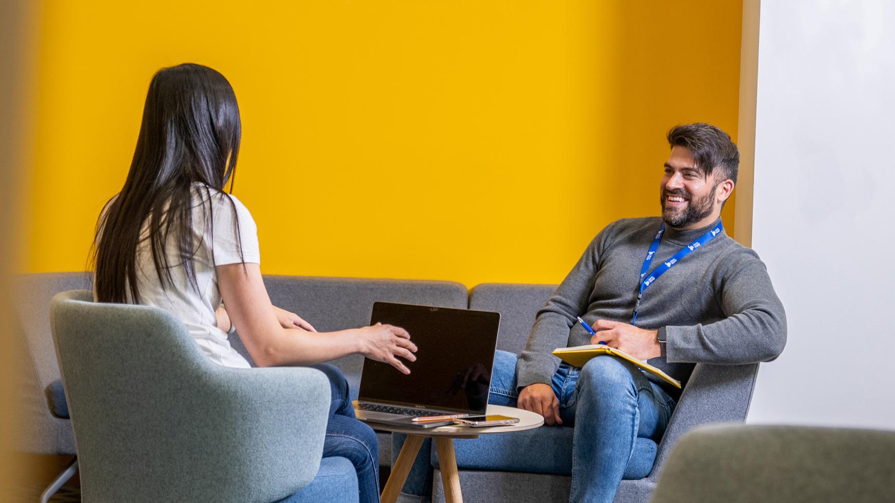 Photo of woman and man talking over laptop